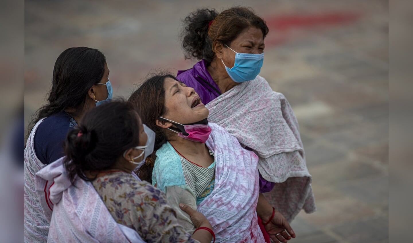 Familieleden van een Nepalees coronaslachtoffer rouwen bij een crematorium in Kathmandu.