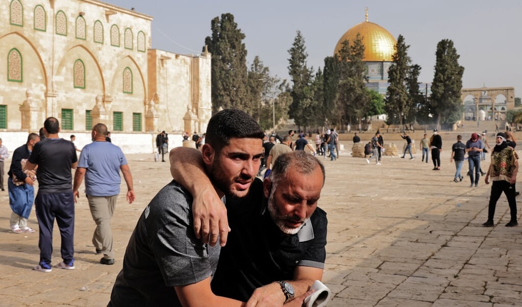 Een Palestijn helpt een man die gewond is geraakt bij een confrontatie met de Israëlische politie bij de Al-Aqsamoskee. (beeld afp / Ahmad Gharabli)