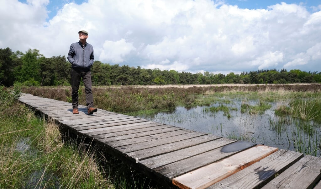 Frans Tijssen wandelend over een vlonderpad in een natuurgebied net buiten Barneveld. (beeld Dick Vos)