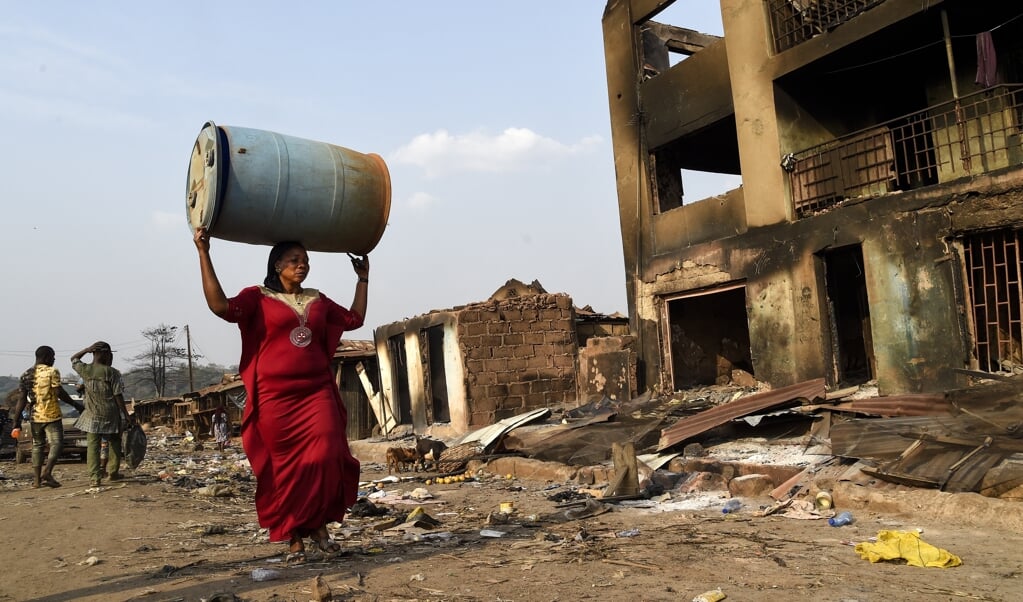De bevolking van Ibadan zoekt naar bruikbare materialen in de door Fulani-herders platgebrande winkels. (beeld Pius Utomi Ekpei / afp)