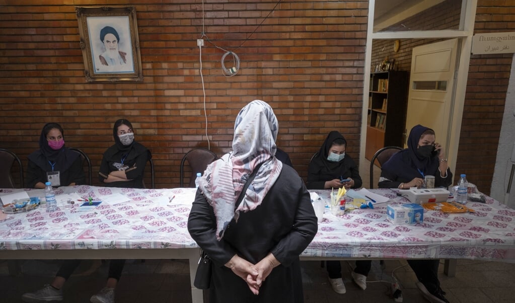 Een Iraanse christelijke vrouw wacht op haar registratie, voordat ze gaat stemmen in een christelijke school in Teheran. (beeld afp / Morteza Nikoubazl)