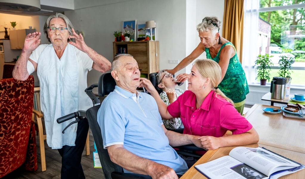 Verpleegkundige Traci Schumaker (roze shirt) werkt zonder mondkapje in verzorgingshuis Het Spijk in Eefde. (beeld Raymond Rutting)