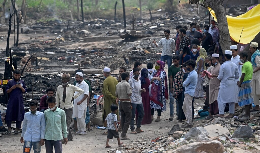 Rohingya-vluchtelingen verzamelen zich bij de verkoolde resten van hun kamp in New Delhi waar een brand uitbrak. (beeld afp / Money Sharma)