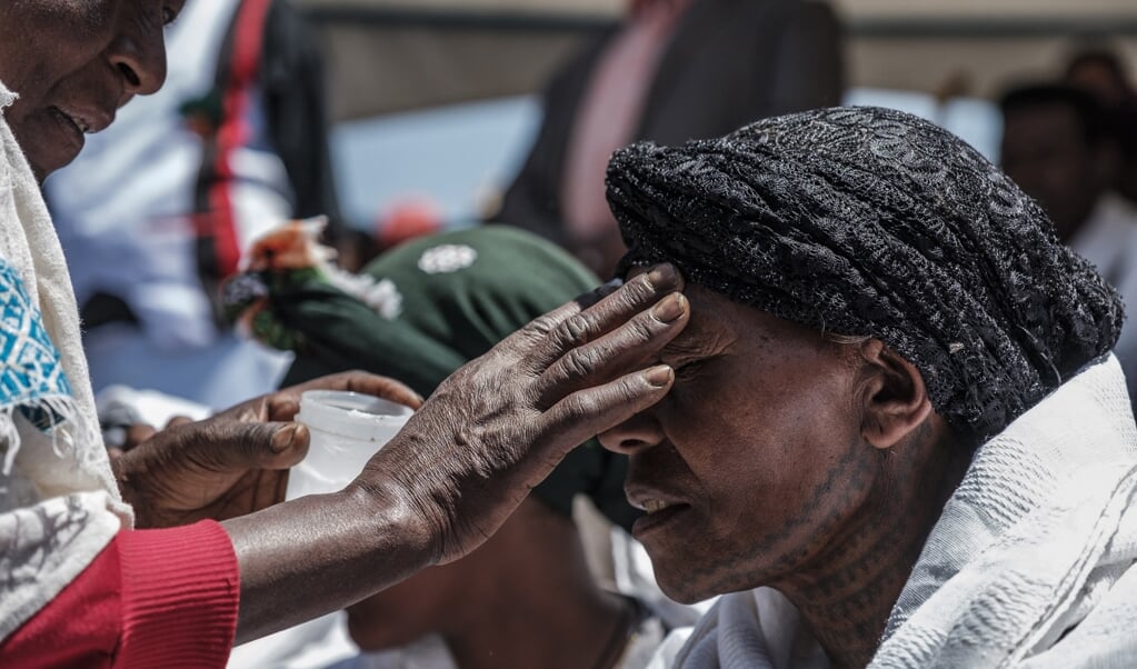Een vrouw in Ethiopië krijgt met olie een kruis op haar voorhoofd getekend tijdens de herdenking van een vliegramp, maart 2020. Het christelijke kruissymbool illustreert een fundamentele omkering van macht, wereldwijd. (beeld afp / Eduardo Soteras)