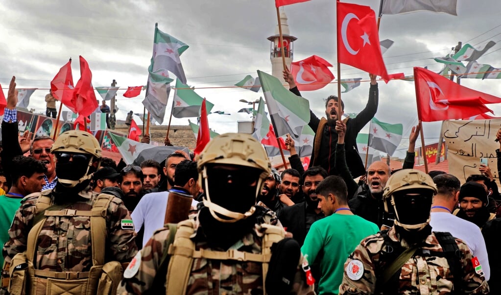 Door Turkije gesteunde Syrische radicaal-islamitische militieleden hijsen hun vlag en die van Turkije in Afrin. Sinds 2018 maakt Turkije samen met de milities de dienst uit in de Syrische regio. (beeld afp / Aaref Watad)