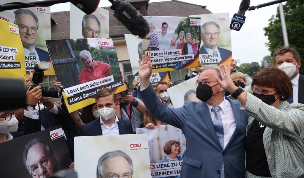 CDU-regeringsleider Reiner Haseloff en zijn vrouw Gabriele Haseloff zwaaien naar publiek en partijleden in na de winst in Saksen-Anhalt. (beeld afp / Ronny Hartmann)