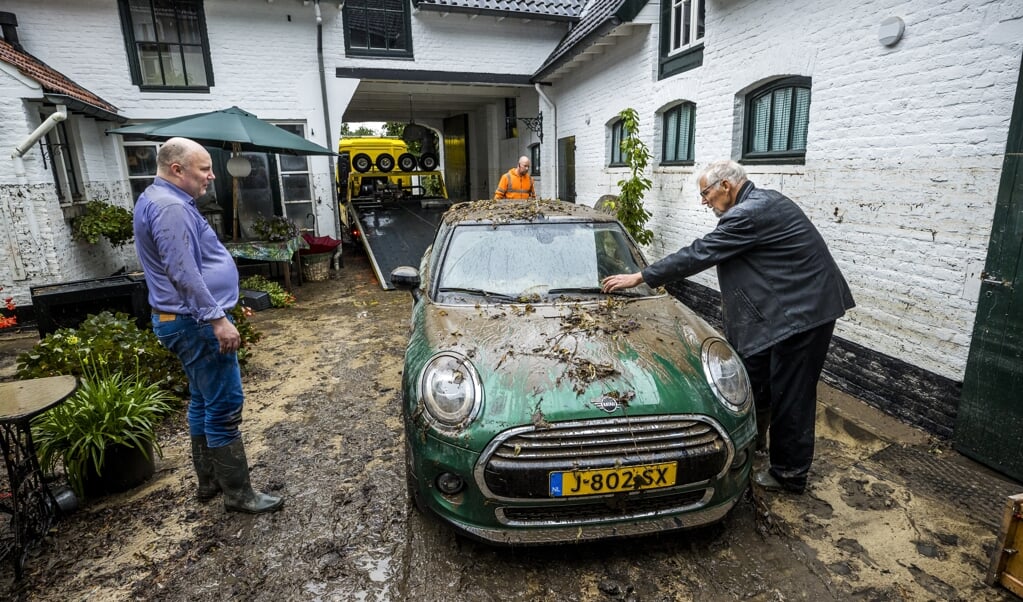 Bewoners van Heerlen bekijken de schade als gevolg van de hevige neerslag bij de monumentale hoeve De Oliemolen. (beeld anp / Marcel van Hoorn)