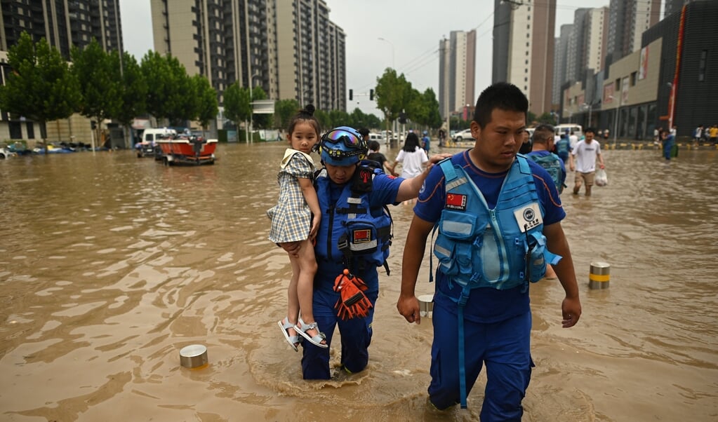 Reddingswerkers helpen een meisje in de ondergelopen straten van Zhengzhou. Hulpvragen en klachten van inwoners worden van sociale media verwijderd door de Chinese overheid. (beeld afp / Noel Celis)