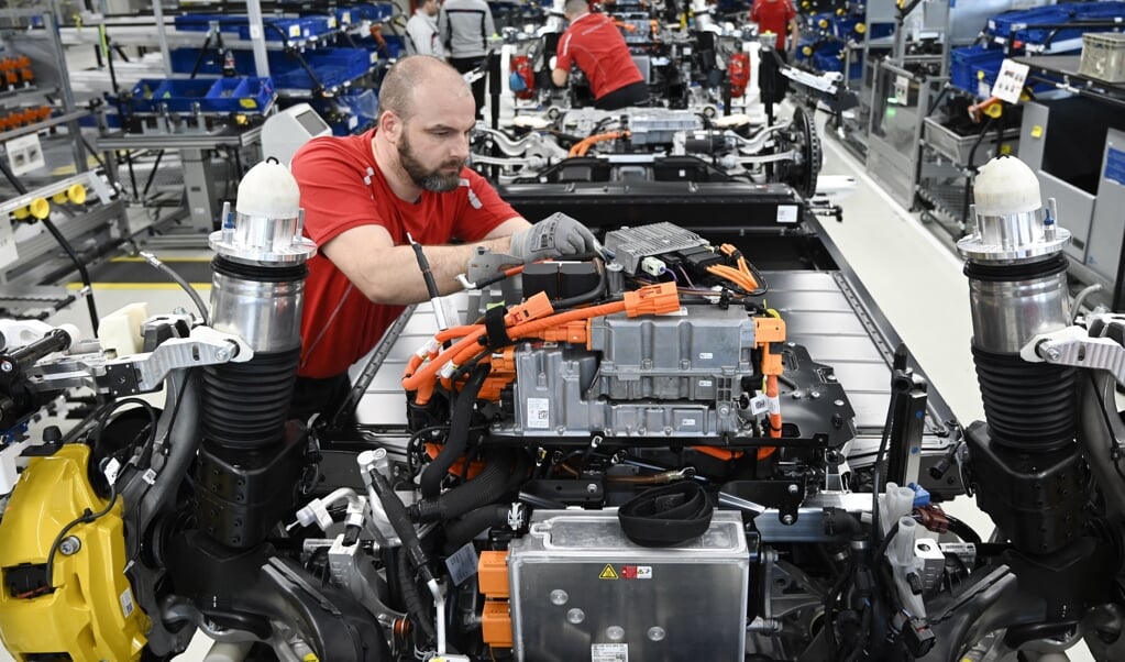 Een medewerker van Porsche werkt aan de productie van een electrische Taycan. De bouw en het onderhoud van elektrische auto's vraagt hoger opgeleid personeel. (beeld afp / Thomas Kienzle)