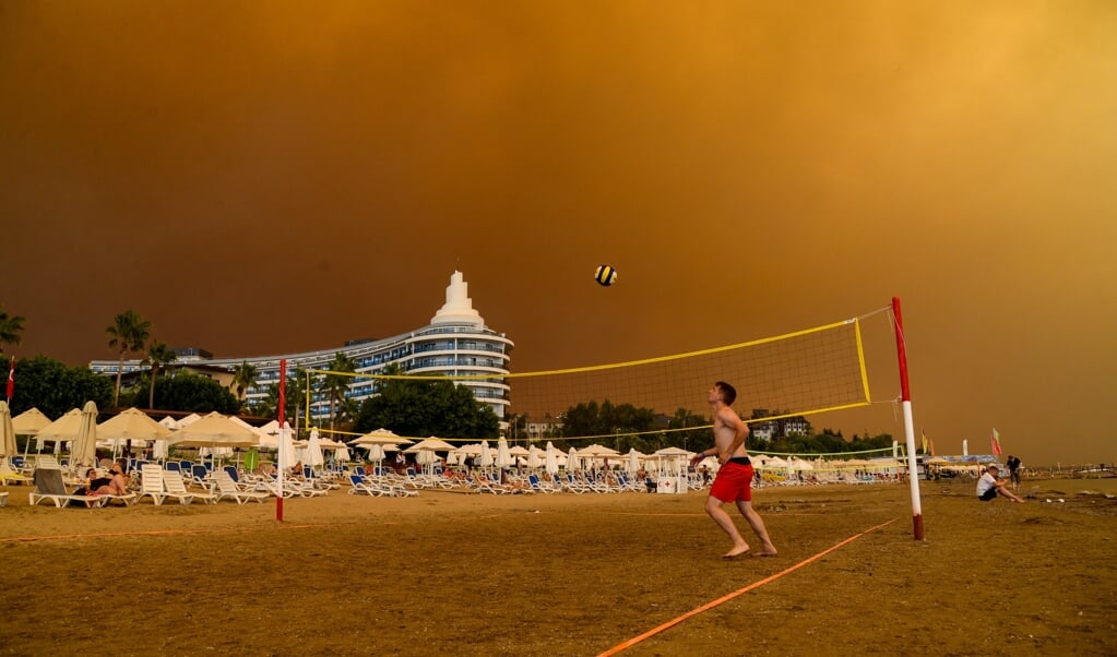 Rookwolken vullen de lucht boven een hotelcomplex en het strand van de Turkse badplaats Manavgat. Vanwege de hittegolf in de regio ontstaan honderden bosbranden. (beeld afp / Ilyas Akengin)