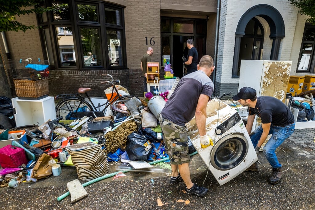 Inwoners ruimen puin na de wateroverlast in Valkenburg aan de Geul. De hevige regenval en overstromingen in Limburg hebben voor veel schade gezorgd. (beeld anp / Marcel van Hoorn)