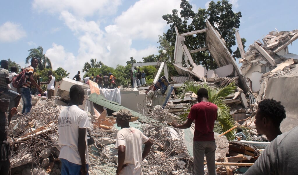 Mensen in Les Cayes, in het zuidwesten van Haiti, zoeken in het puin van een hotel naar overlevenden. (beeld afp / Stanley Louis)