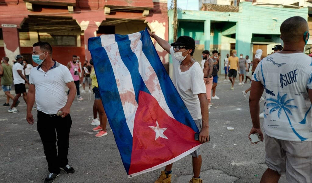 Een demonstrant wappert met de Cubaanse vlag tijdens de protesten van 11 juli. (beeld Thousands of Cubans Took Part in Rare Protests Sunday Against the Communist Government, Marching Through a Town Chanting 'down With the Dictatorship' and 'we Want Liberty.' Adalberto Roque / afp)