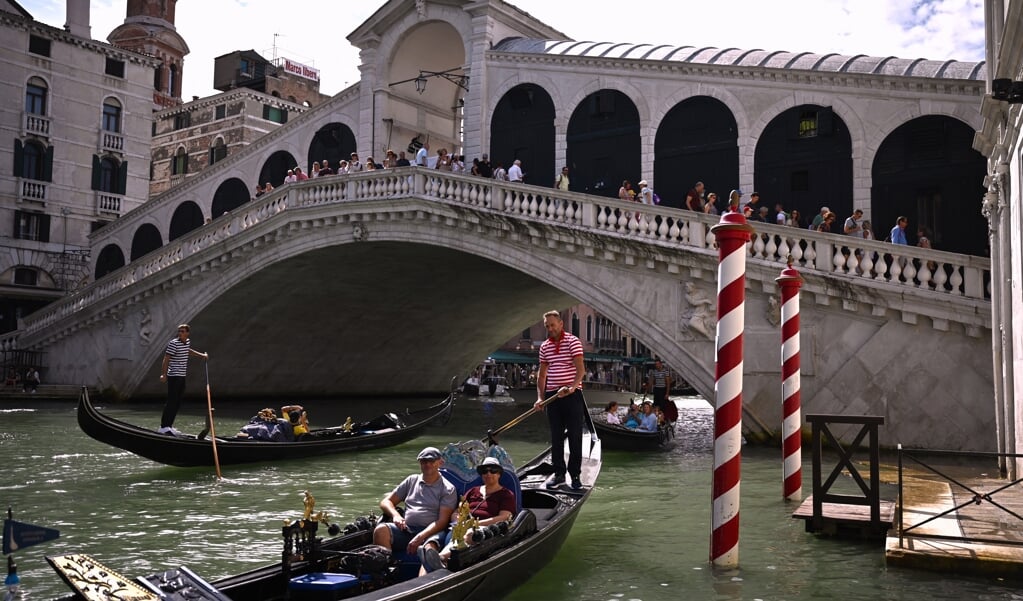 Toeristen varen met een gondel door Venetië.  (beeld afp / )