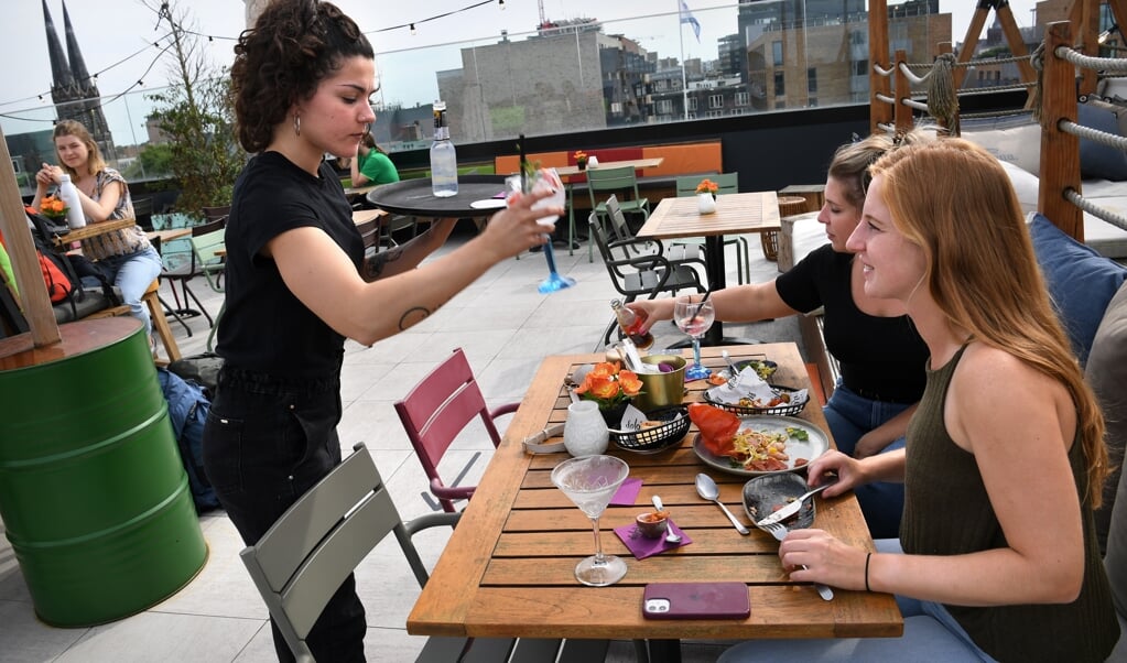 Gasten bij rooftopbar Doloris in Tilburg. De nieuwe maatregelen zijn voor niemand te handhaven, zeggen horecaondernemers. (beeld Marcel van den Bergh)