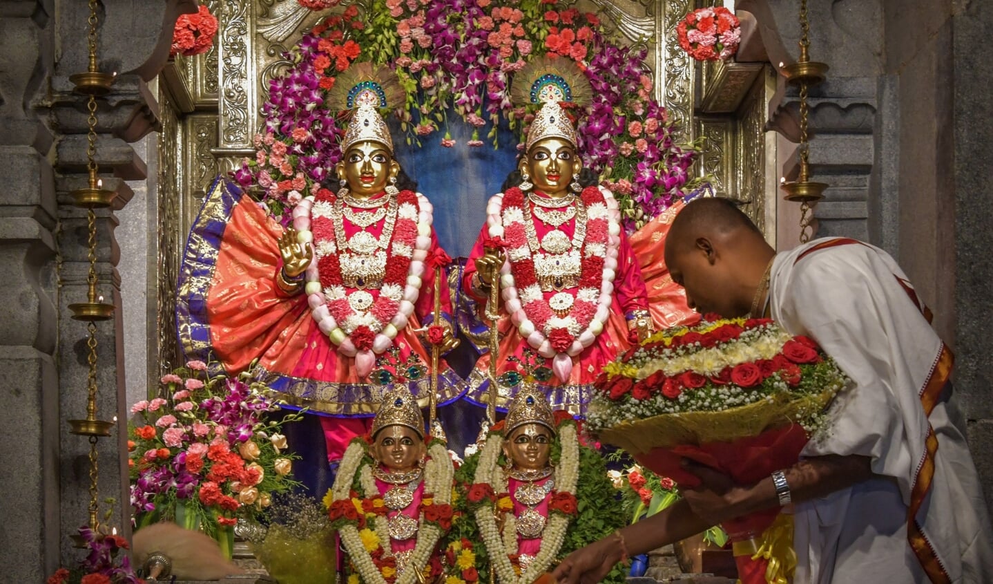 Een hindoepriester voert een ritueel uit bij de hindoegoden Krishna en Balarama. 