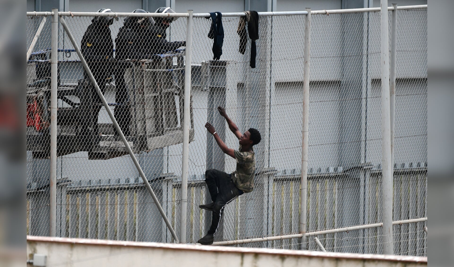 Rond en binnen Europa verschijnen steeds meer hekken. Beeld: een jongere probeert een hek bij de Spaanse exclave Ceuta over te klimmen.