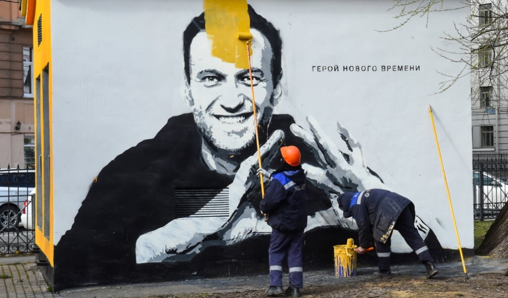 Een graffiti-tekening van de Russische oppositieleider Alexej Navalni wordt verwijderd in Sint-Petersburg. (beeld afp / Olga Maltseva)