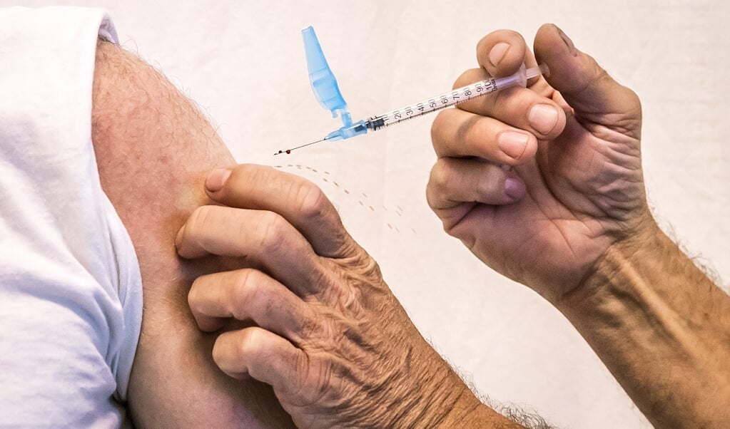 Een bewoner uit een Haagse wijk laat zich vaccineren in een gezondheidscentrum.  (beeld anp / Remko de Waal)