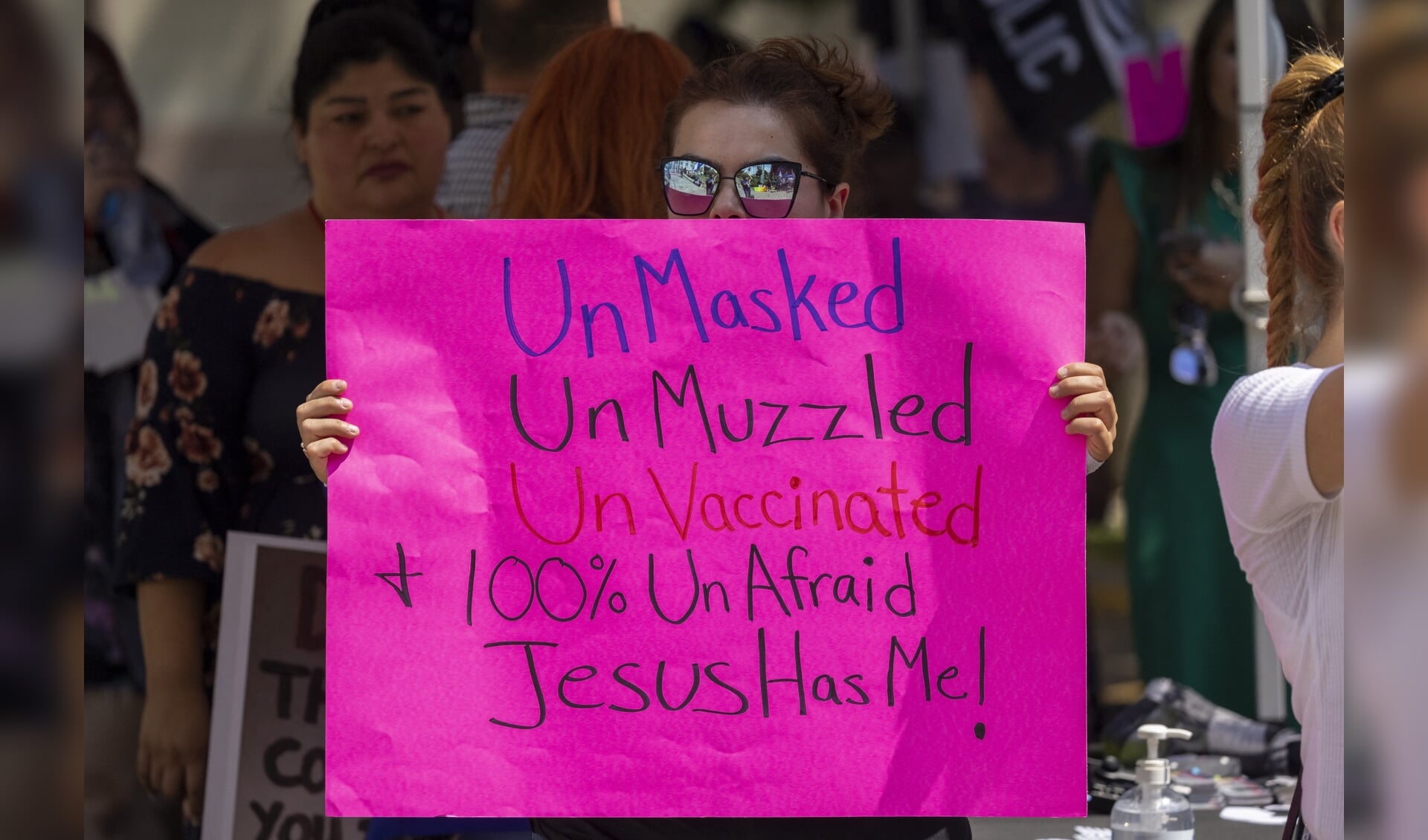 Een vrouw in Los Angeles houdt een protestbord omhoog waarop staat dat zij niet gevaccineerd hoeft te worden of een masker hoeft te dragen, omdat Jezus haar zal beschermen tegen het coronavirus.