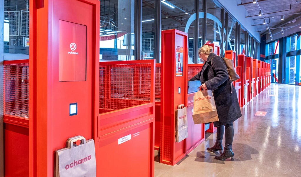 Een klant haalt een bestelling af, door een robot in een krat geplaatst en via een rolband tot haar gebracht. (beeld Raymond Rutting)