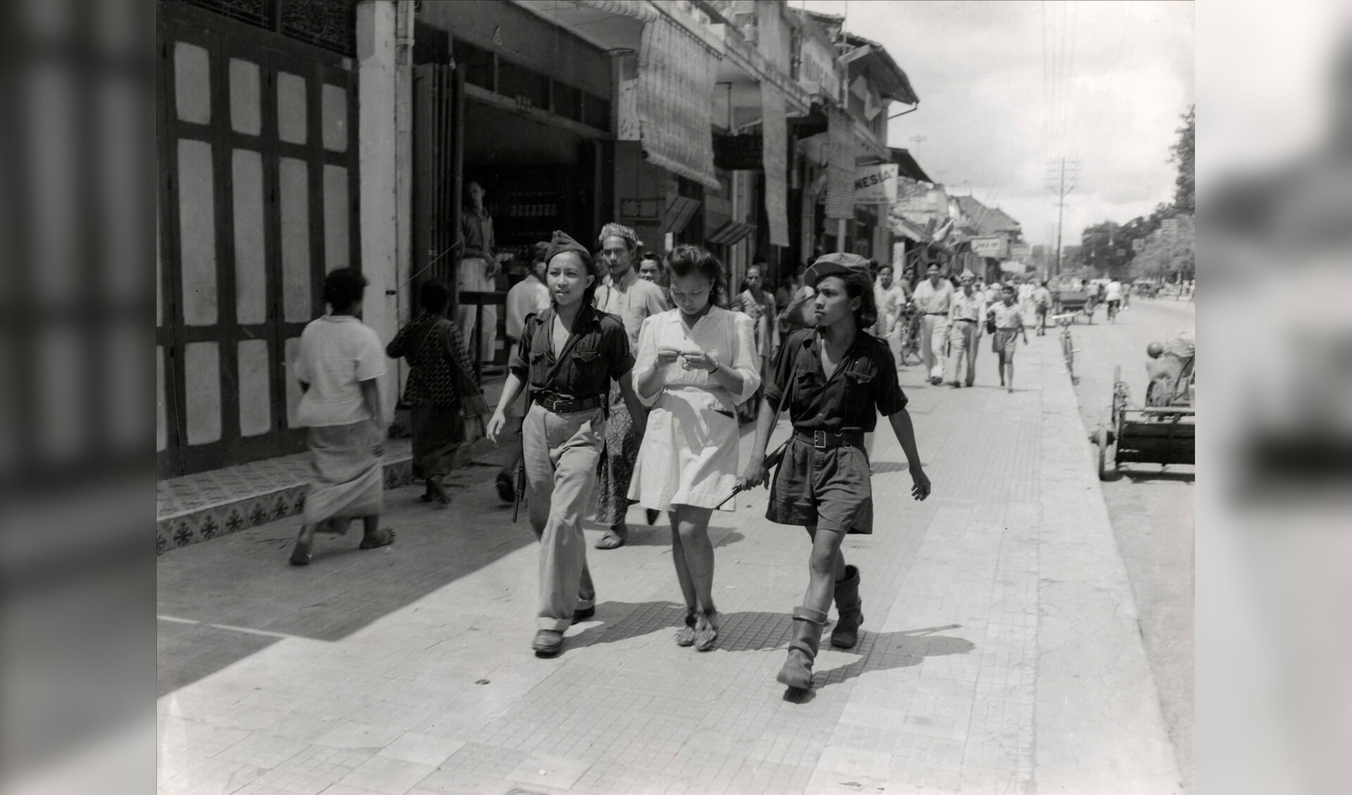 Drie jonge Indonesiërs op straat, onder wie twee Republikeinse vrijwilligers uit Sulawesi, leden van de gewapende jeugdorganisatie KRIS, op verlof in Yogyakarta, december 1947.