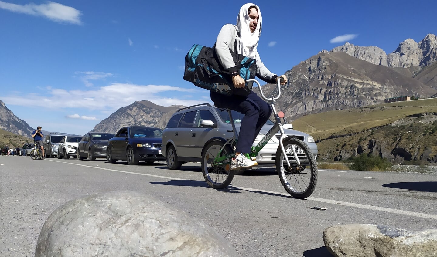 Een Russische man steekt met een fiets de grens over bij Verkhny Lars, bij de grensovergang tussen Georgië en Rusland. (AP Photo)