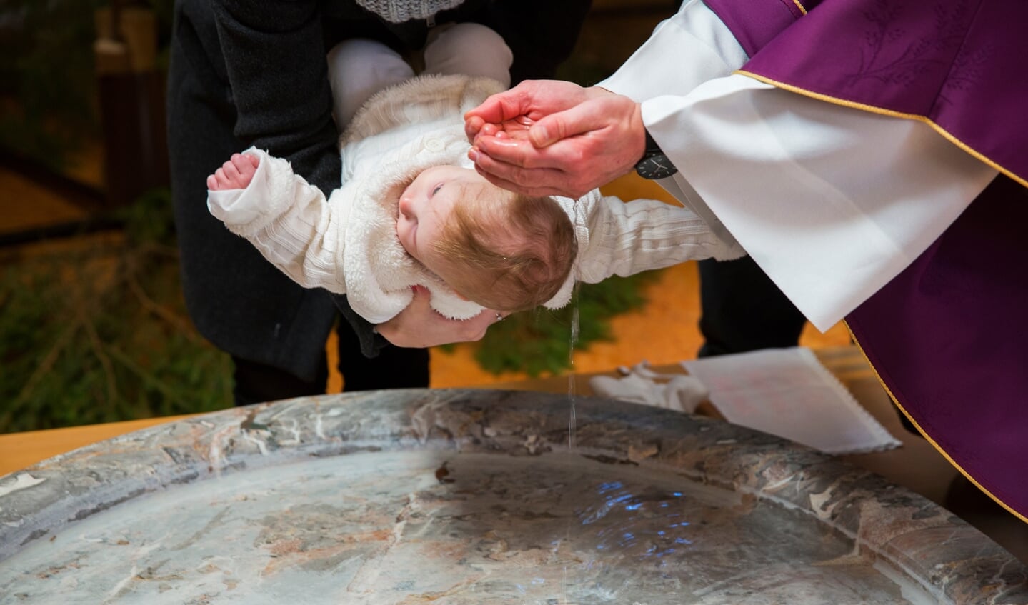 Een kinderdoop in een traditionele kerk, door besprenkeling met water.