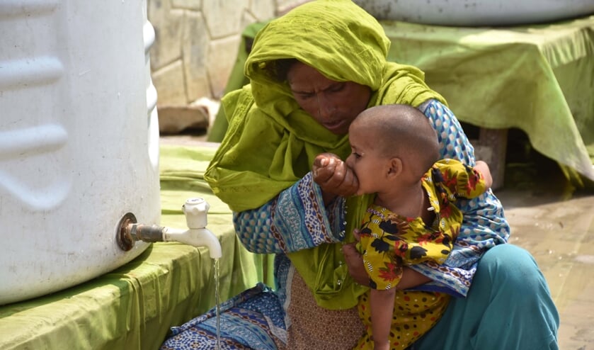 Een vrouw geeft haar kind wat te drinken in een tentenkamp. In het rampgebied is vooral de situatie voor kleine kinderen, zwangere vrouwen en moeders nijpend.