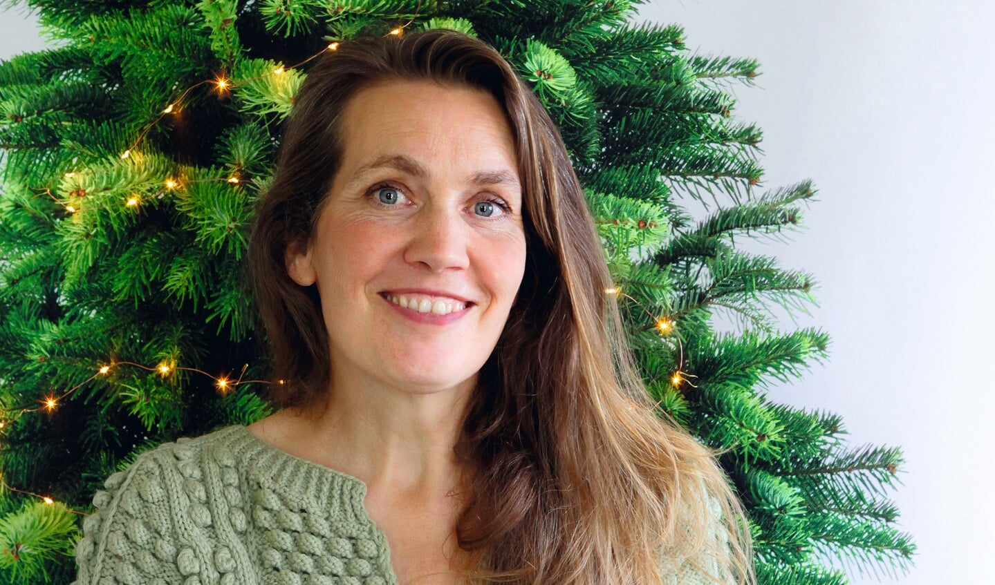 Suseela Gorter bij haar kerstboomwandkleed waarop je zelf LED-lichtjes en kerstballen kunt spelden.