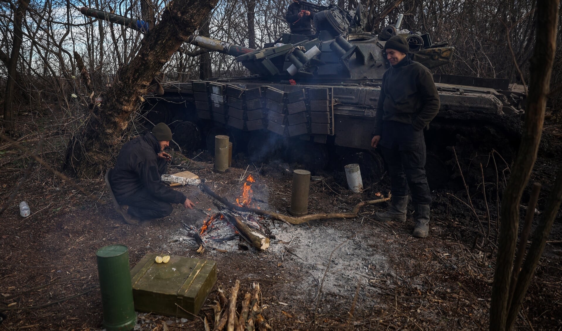 Oekraïners warmen zich aan een vuurtje naast hun tank.