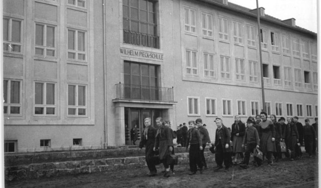 Een groep leerlingen loop voor de Wilhelm Pieck Schule langs.  (beeld bundesarchiv duitsland)