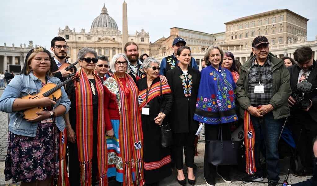 De delegatie van de Métis met haar voorzitter, Cassidy Caron (vierde van rechs met zwarte kleding) voor het Sint-Pietersplein in Rome na de audiëntie met de paus.  (beeld afp / Andreas Solaro)