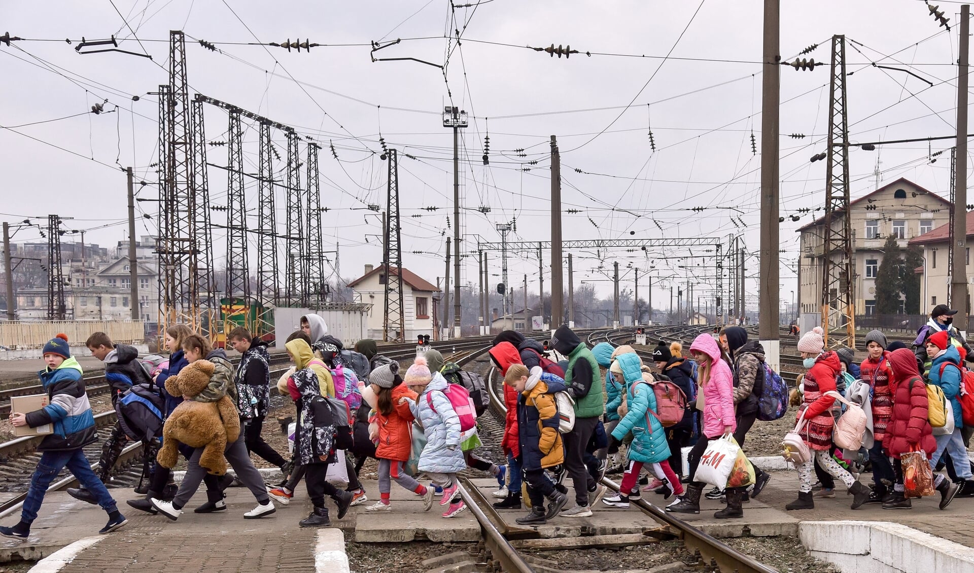 Geëvacueerde kinderen uit een weeshuis in het dorp Hoeljajpole steken bij het station van Lviv het spoor over.