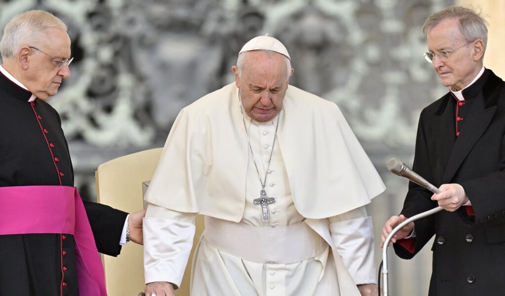 Paus Franciscus heeft duidelijk pijn aan zijn knieën terwijl hij opstaat tijdens de algemene audiëntie op het Sint-Pietersplein op 20 april.   (beeld afp / Alberto Pizzoli)