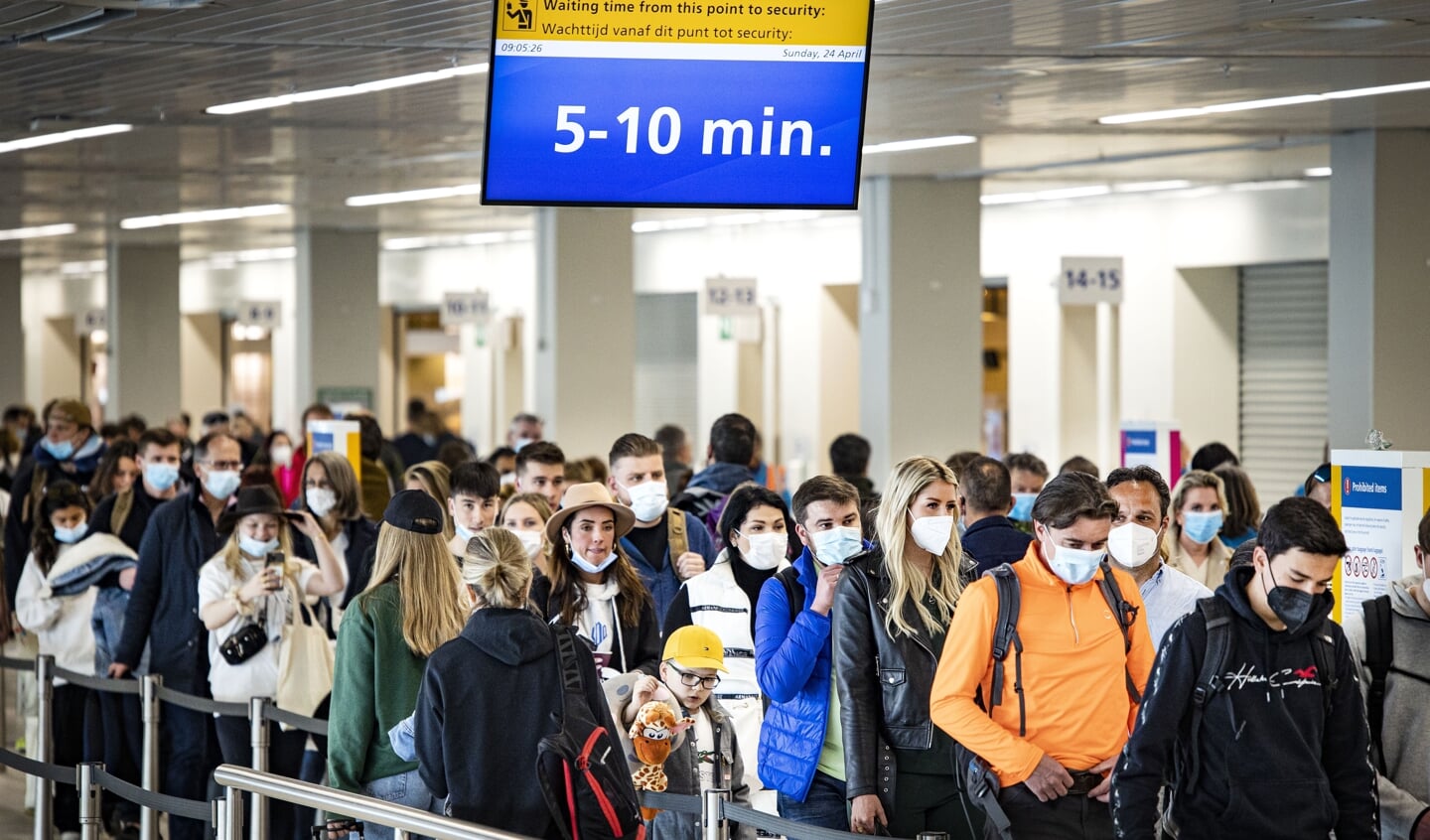 Reizigers in een vertrekhal op Schiphol. Na de staking door personeel van KLM een dag eerder waardoor veel vluchten uitvielen, waarschuwt Schiphol dat het extra druk kan zijn op de luchthaven.