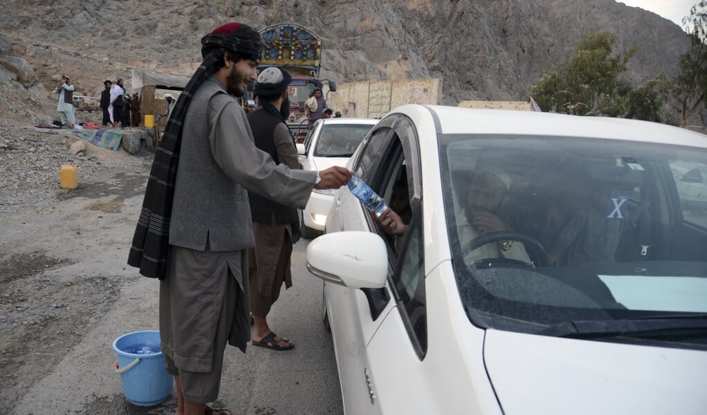 Strijders van de Taliban delen water uit in Kandahar. In Afghanistan staat de godsdienstvrijheid sterk onder druk, meldt het Amerikaanse USCIRF.  (beeld Javed Tanveer / afp)