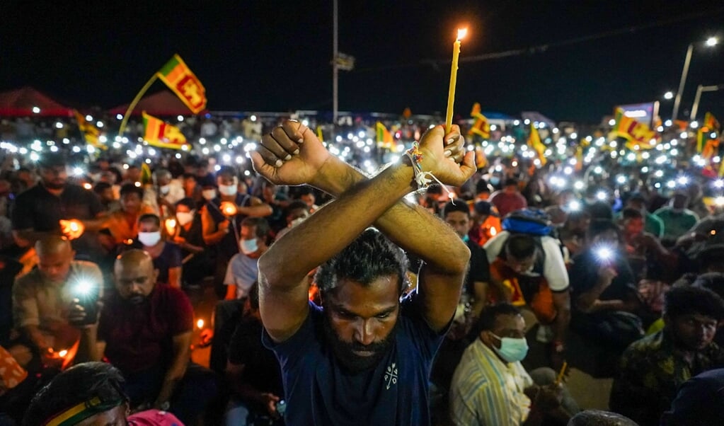 Betogers in de Sri Lankaanse hoofdstad Colombo dragen kaarsen ter herdenking van de slachtoffers van de aanslagen op paaszondag 2019.  (beeld afp)