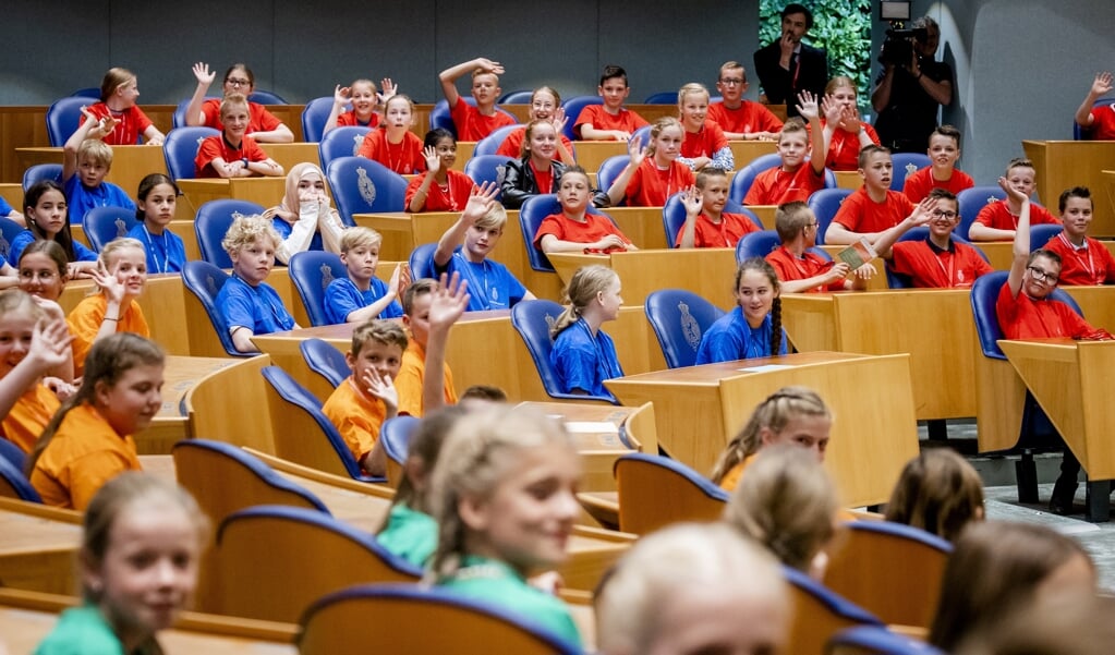 Scholieren in de Tweede Kamer tijdens het Kindervragenuur. Kinderen uit groep 7 en 8 zitten in de blauwe Kamerzetels en bestoken bewindspersonen met vragen over thema's als de democratie, dierenwelzijn, landbouw, milieu en onderwijs. (beeld anp / Sem van der Wal)