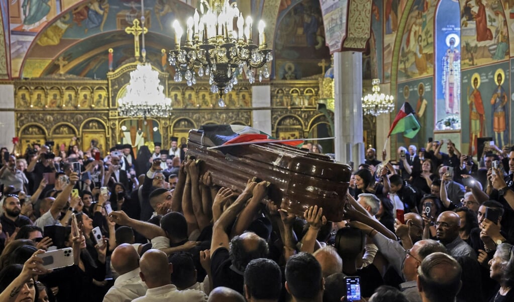 De kist met daarin het lichaam van Shireen Abu Akleh wordt de Grieks-Katholieke Kerk in Jeruzalem binnengedragen. (beeld Ronaldo Schemidt / afp)
