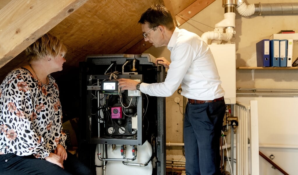 Een medewerker van Vattenfall legt een inwoner van Heemskerk de werking van een warmtepomp uit.  (beeld anp / Sander Koning)
