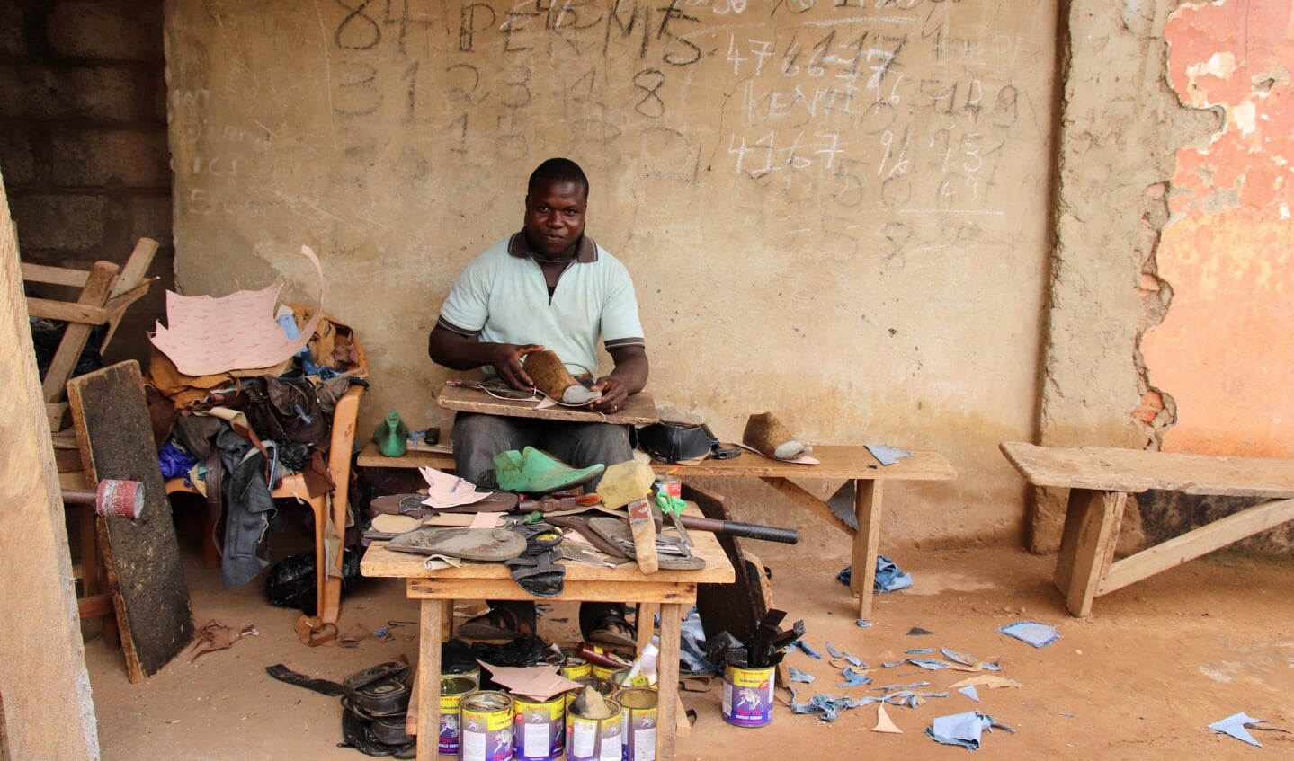 Een schoenmaker aan het werk aan de publieke weg in Kpalimé. 