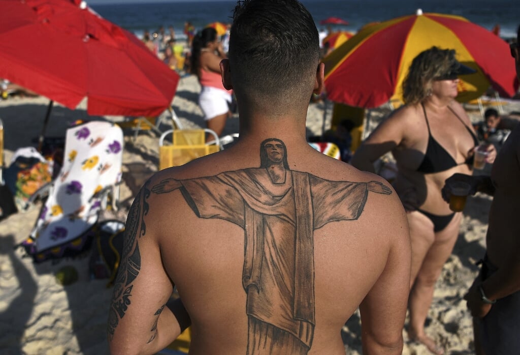 Een Braziliaan met een Jezus-tatoeage op het strand.  (beeld afp / Carl de Souza )