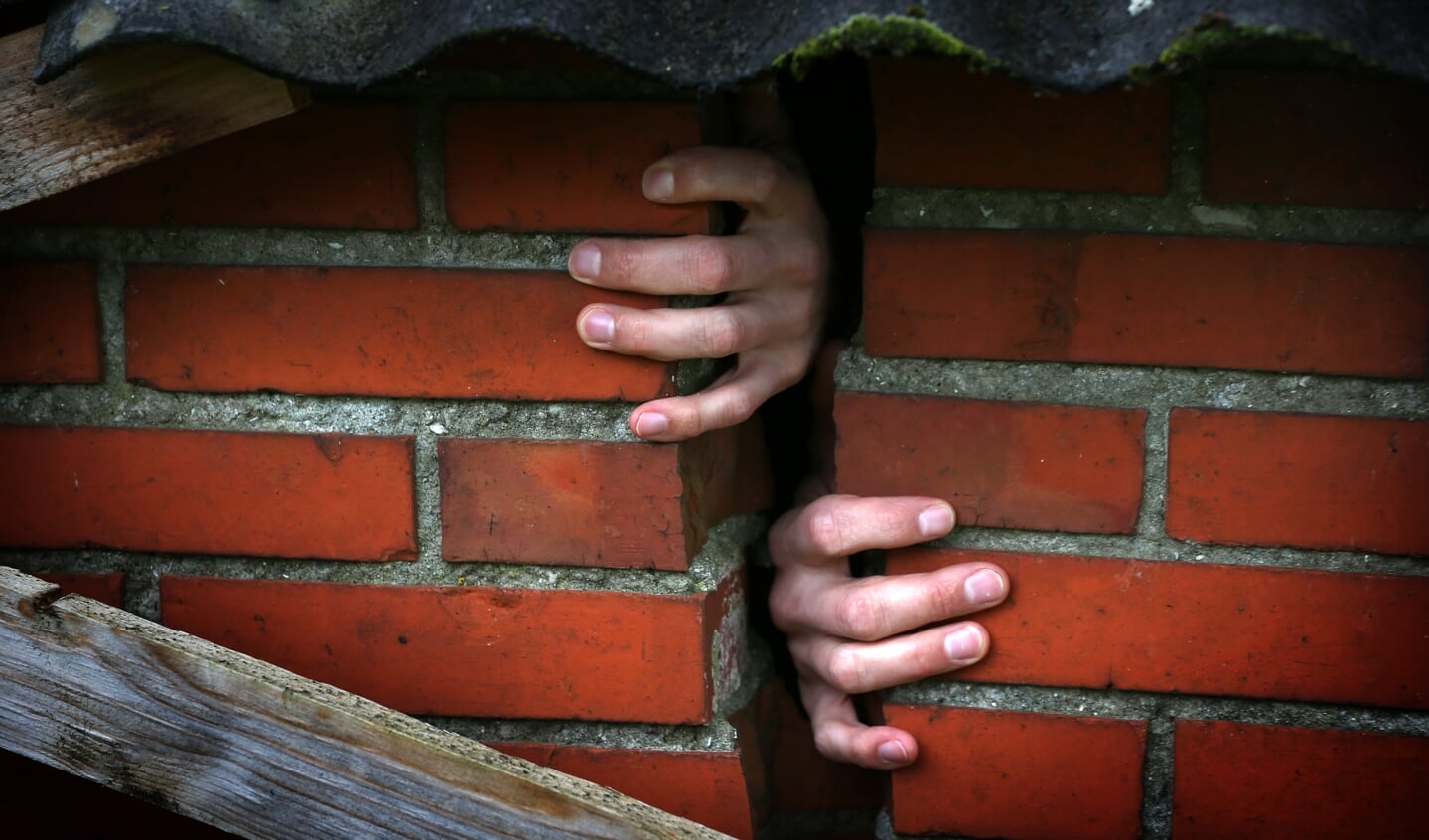 Handen zijn zichtbaar door een scheur in de muur van een woning in Bedum.