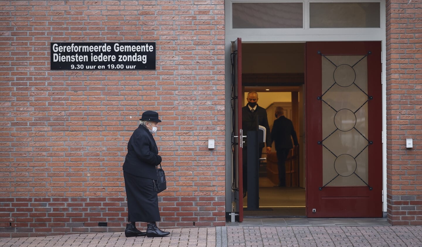 Een vrouw gaat het kerkgebouw van de Gereformeerde Gemeente in Barneveld binnen.