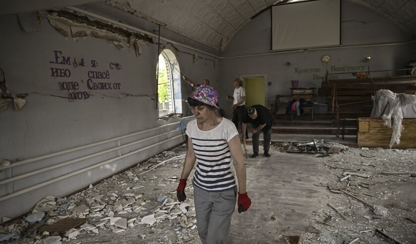 Een vrouw in een verwoeste kerk in de stad Druzhkivka, in de regio Donbas.  (beeld Aris Messinis / afp)