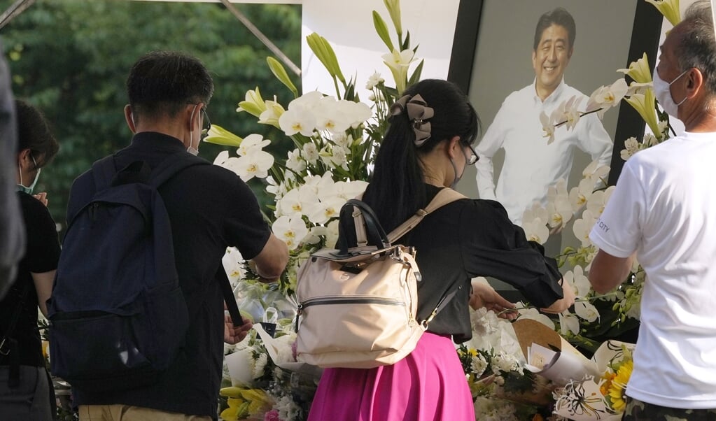 Mensen leggen bij de Zojoji-tempel bloemen neer voor de Japanse oud-premier Abe. (beeld epa / Kimimasa Mayama)