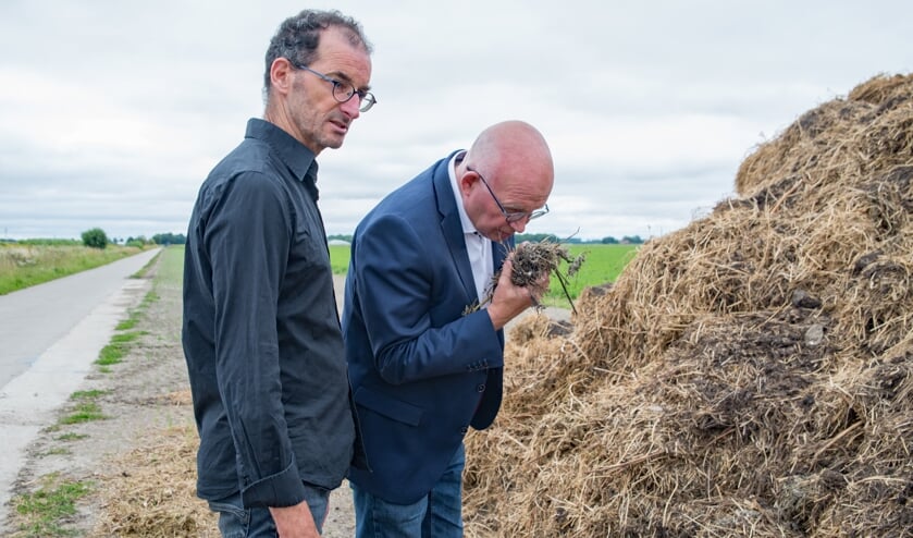 Minister Henk Staghouwer van Landbouw ruikt aan de plantaardige compost. Links akkerbouwer Joost van Strien.