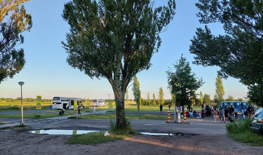Asielzoekers wachten voor het hek van het aanmeldcentrum tot ze naar crisisnoodopvanglocaties worden gebracht.