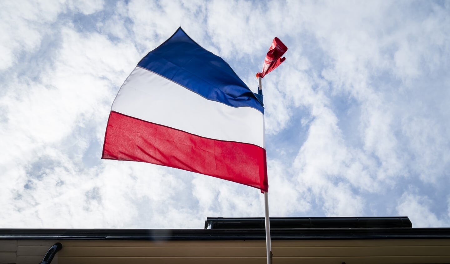 De omgekeerde Nederlandse vlag hangt uit aan de gevel van een woning.